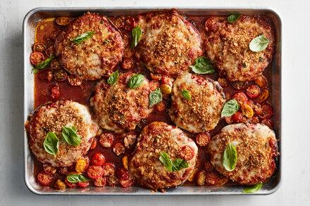 یک سینی فر پر از قارچ پارمیجینا با برگهای ریحان پراکنده شده است.